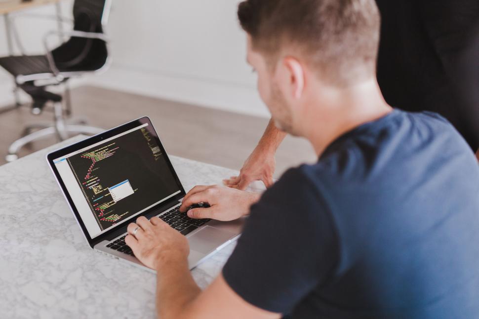 Free Image of A man sitting at a table using a laptop 