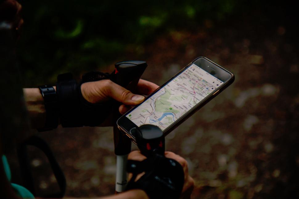Free Image of A person holding a phone and walking sticks 