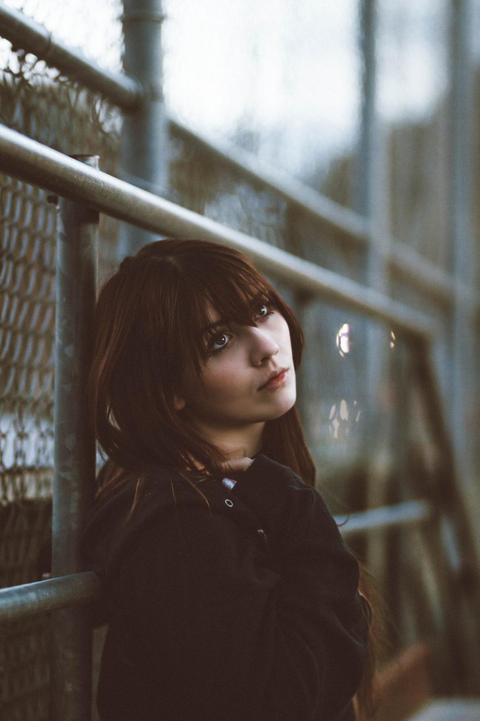 Free Image of A woman leaning against a fence 