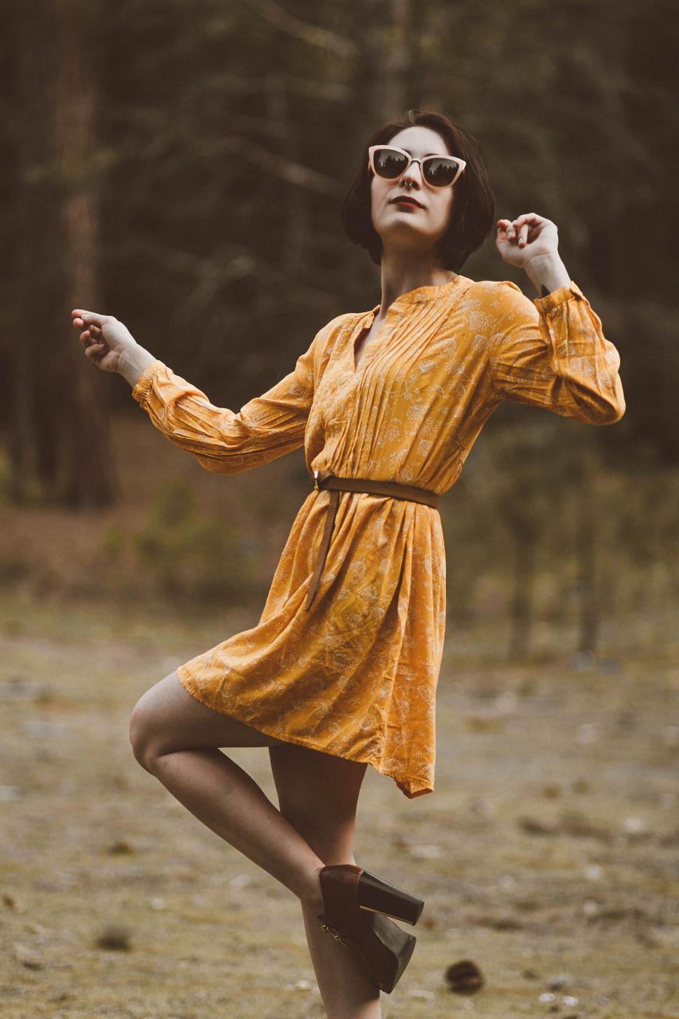 Free Image of A woman wearing a yellow dress and sunglasses 