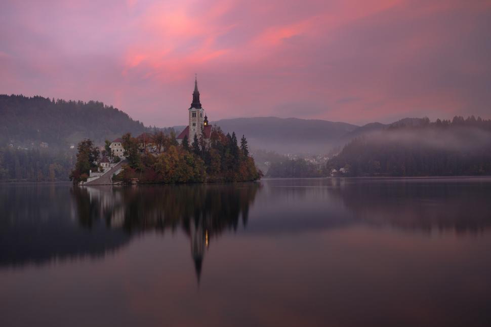 Free Image of A building on an island with trees and buildings in the distance 