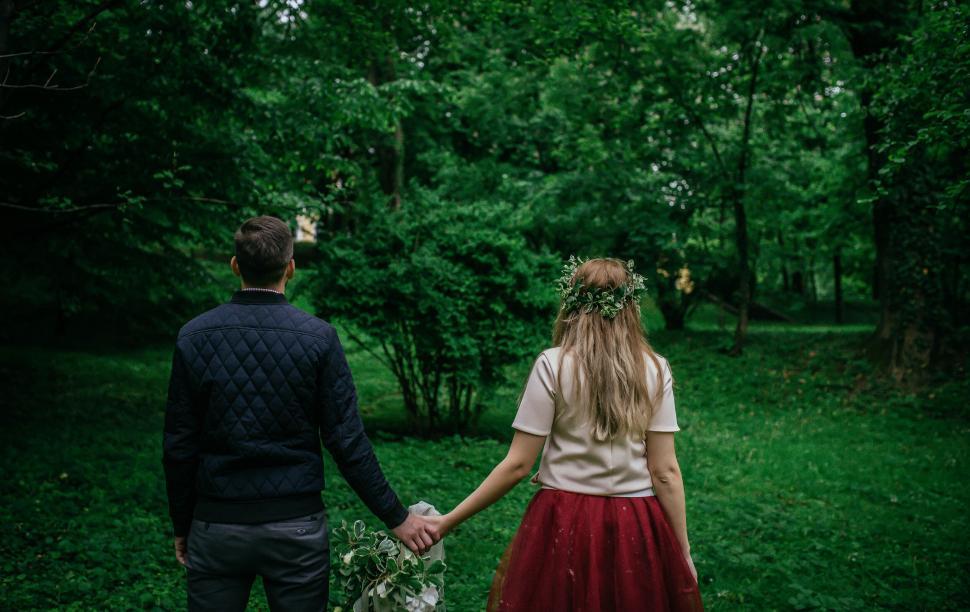 Free Image of A man and woman holding hands in a forest 