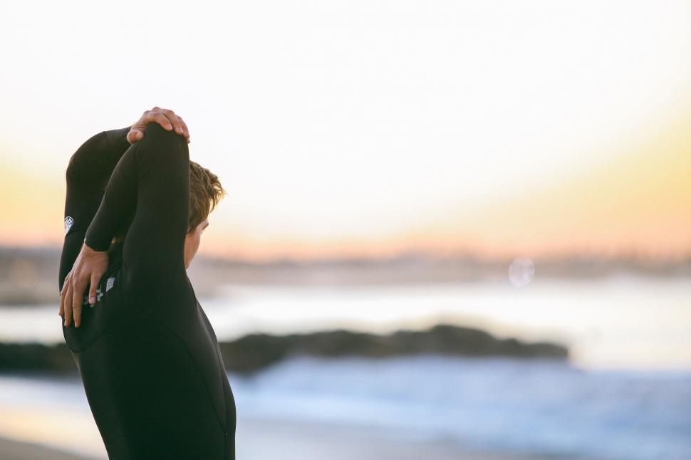 Free Image of A person stretching on the beach 