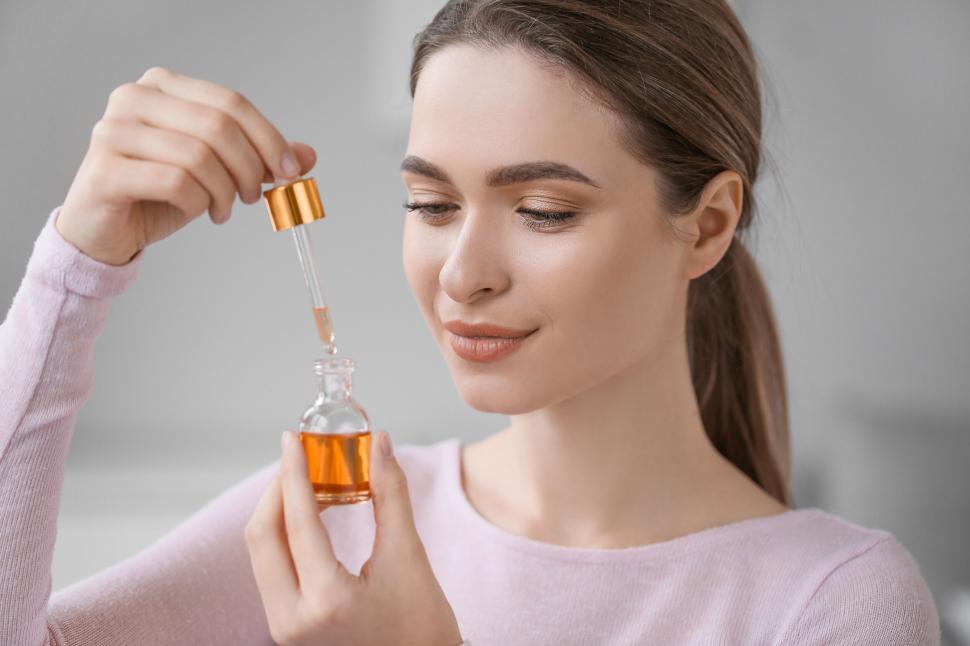 Free Image of A woman holding a bottle of liquid 