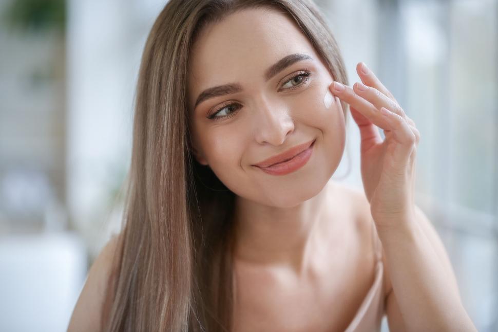 Free Image of A woman applying cream on her face 