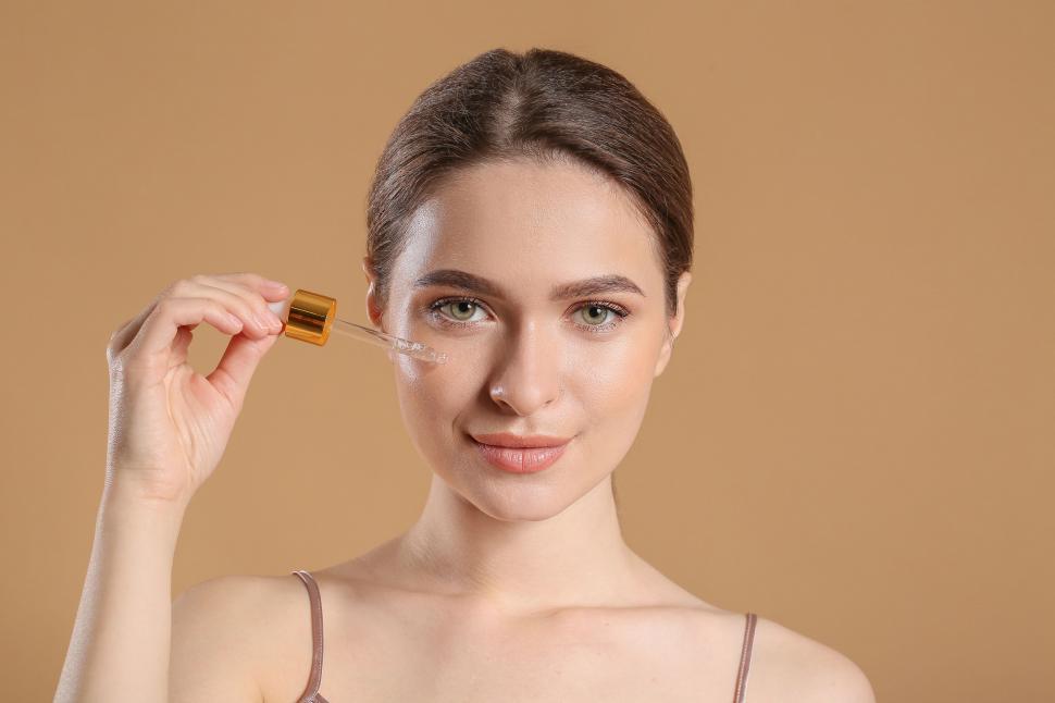 Free Image of A woman applying a dropper on her face 