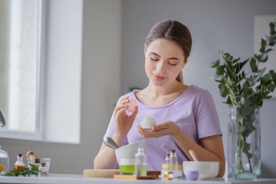 Free Image of A woman holding a small jar of cream 
