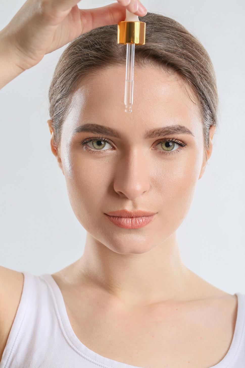 Free Image of A woman holding a dropper over her forehead 