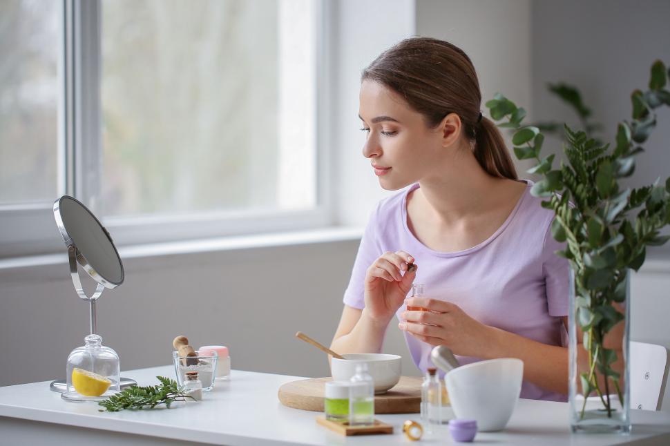 Free Image of A woman sitting at a table holding a small bottle of oil 