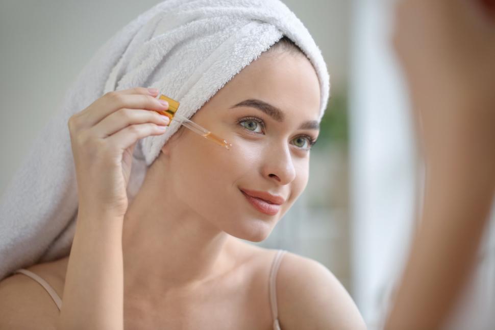 Free Image of A woman applying a dropper on her face 