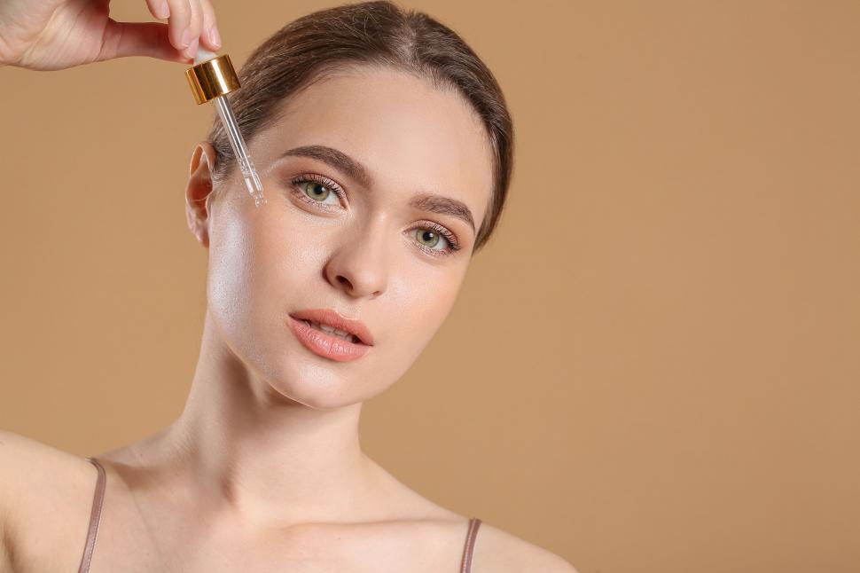 Free Image of A woman applying a dropper on her face 