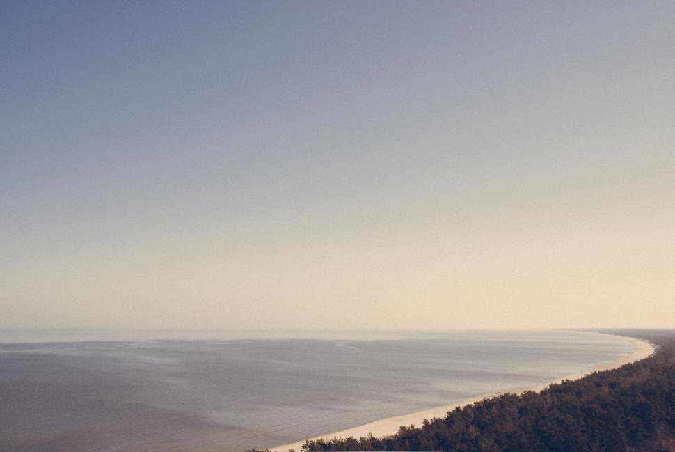 Free Image of Panoramic view of beach with forested coastline 