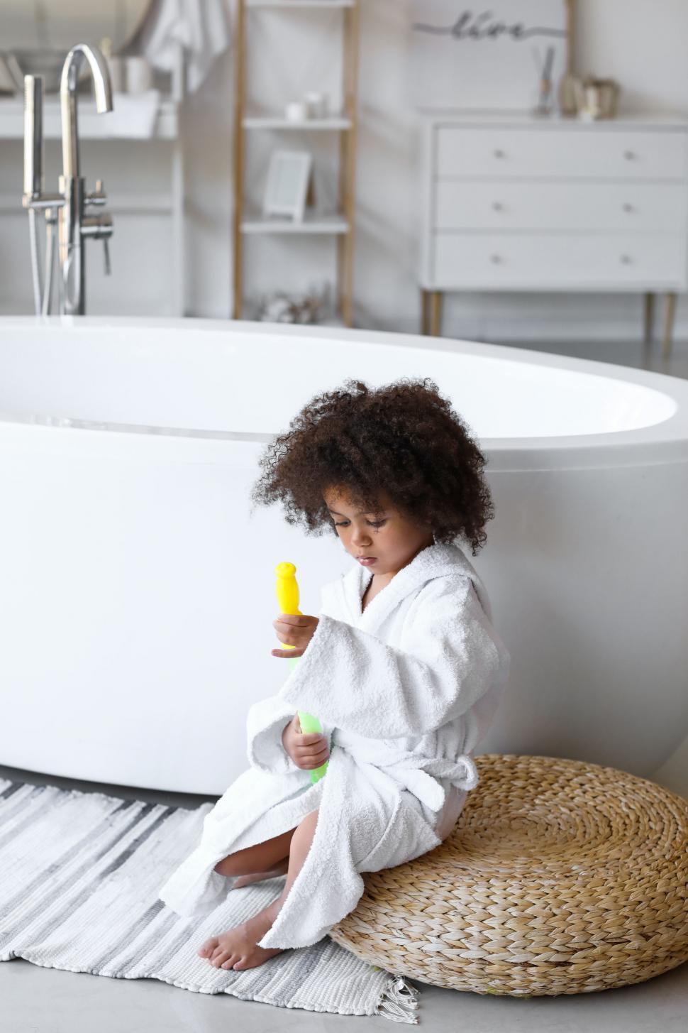 Free Image of Little girl sits on wicker stool with bottle 