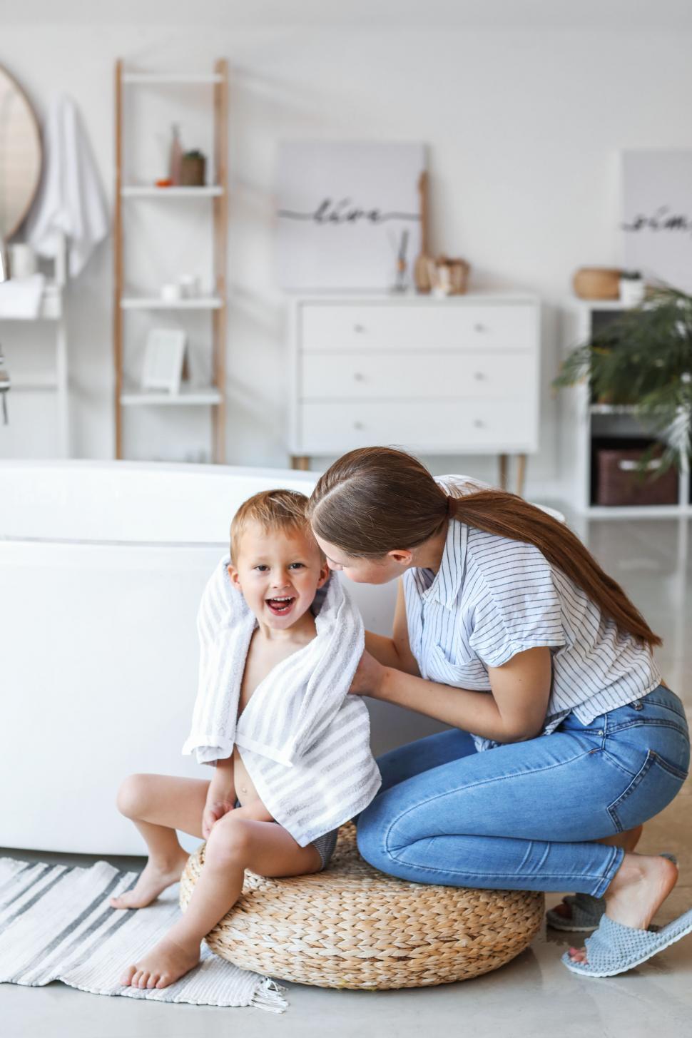 Free Image of Child wrapped in a towel sitting on a stool 
