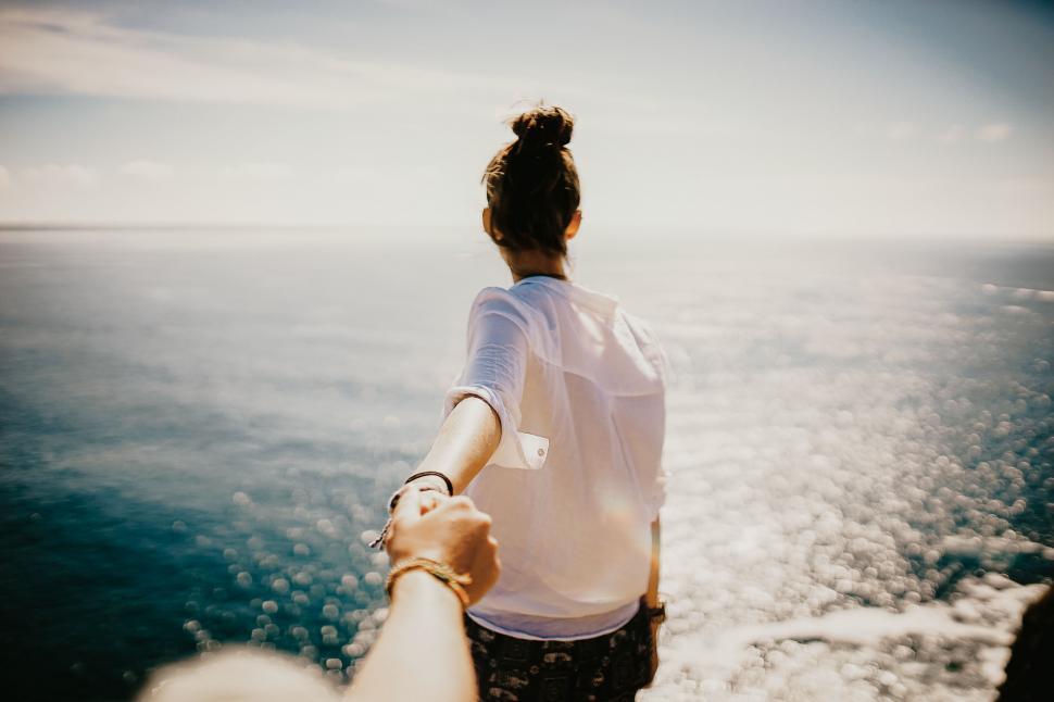 Free Image of Woman leading partner towards the ocean 