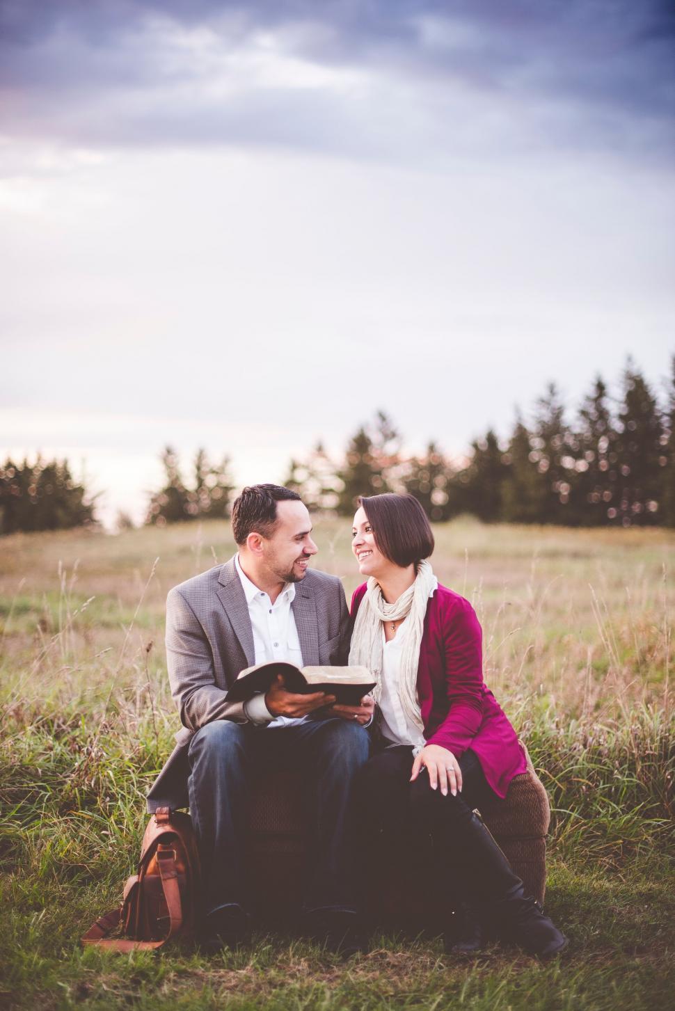 Free Image of Couple reading together in a meadow 