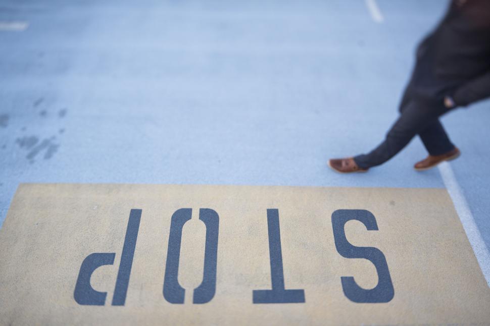 Free Image of Stop sign painted on street with feet 