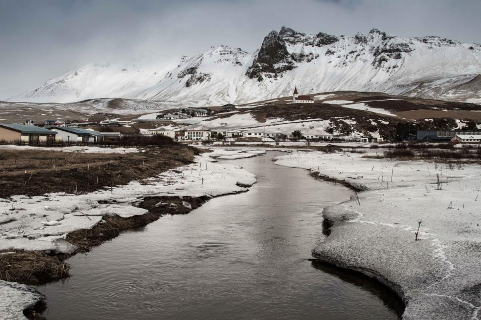 Free Image of Snowy village by a river and mountains 