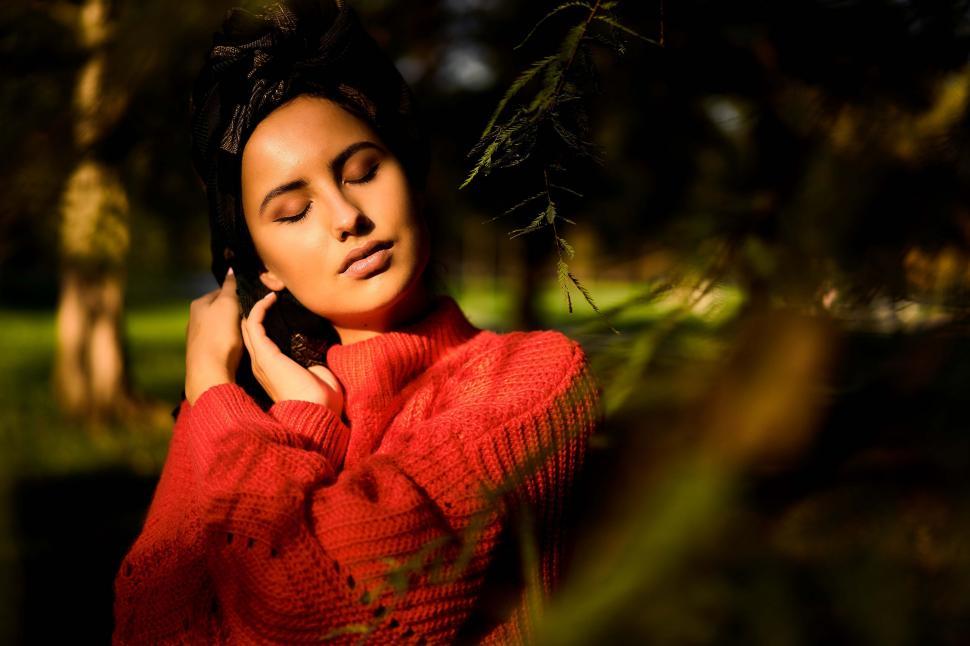 Free Image of Woman posing in sunlight with eyes closed 