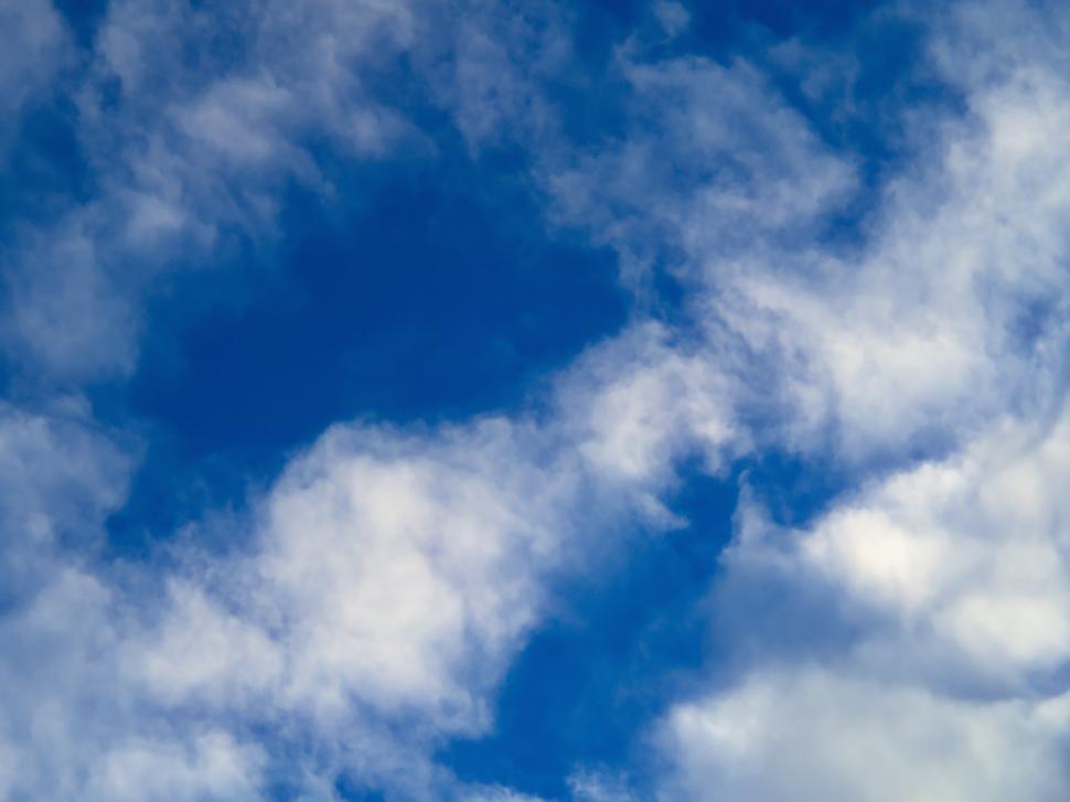 Free Image of Fluffy white clouds scattered across blue sky 