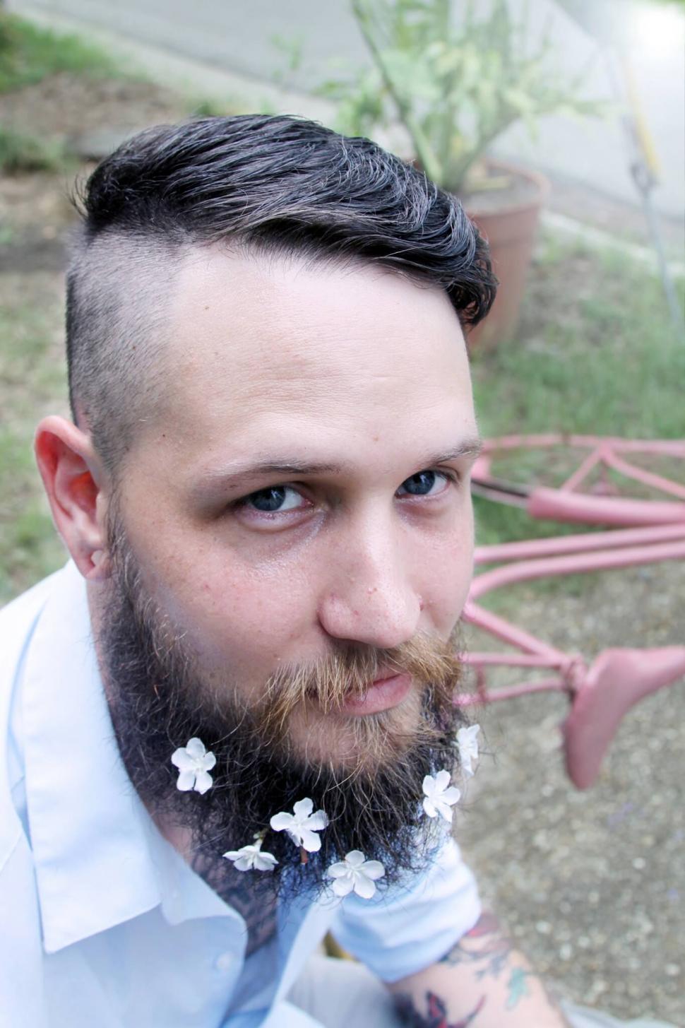 Free Image of Bearded man with flowers in beard looking up 