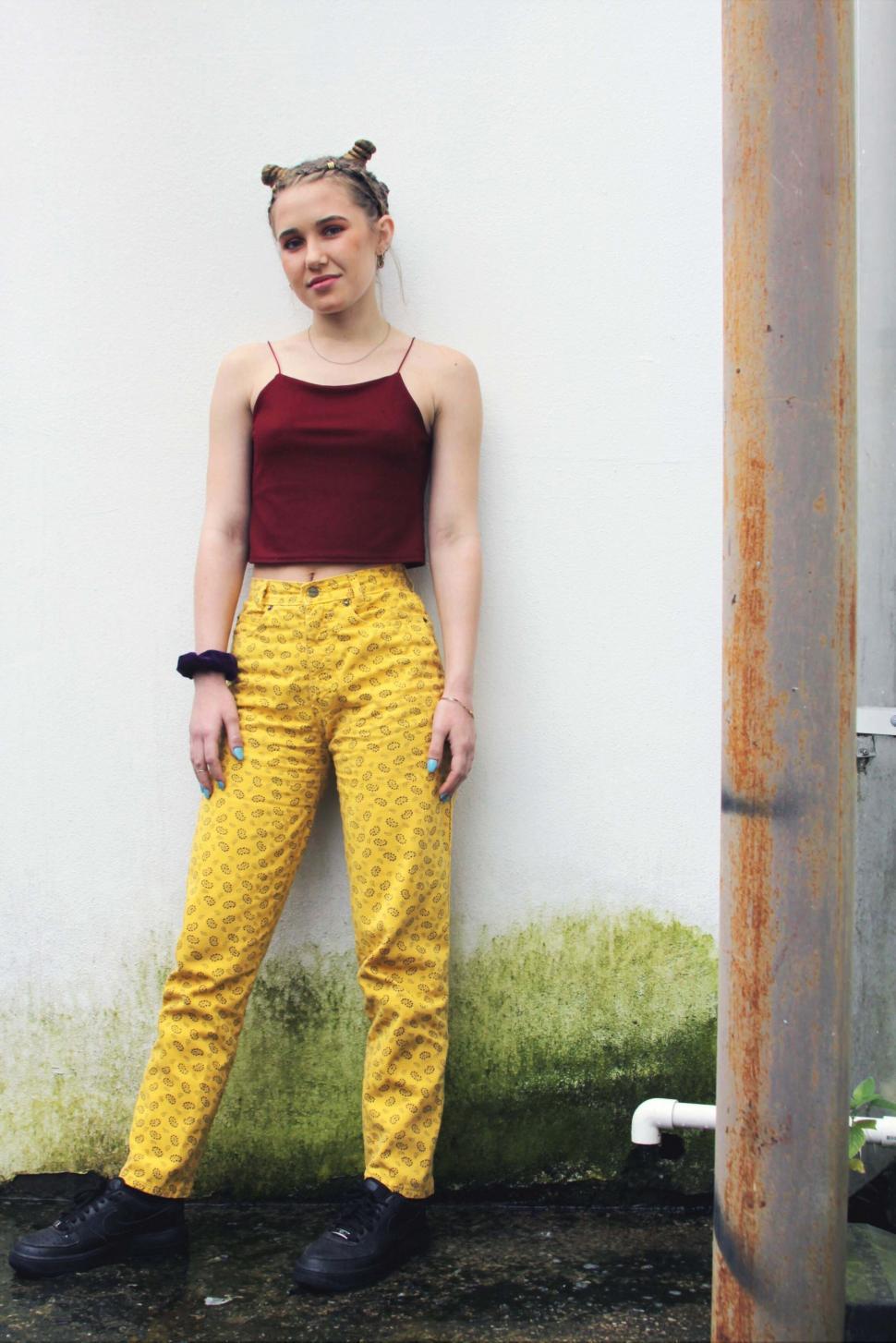 Free Image of Young woman posing by a rusty drainpipe 