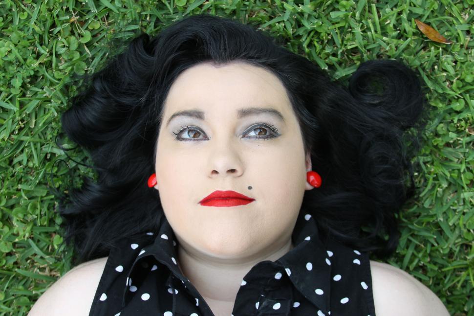 Free Image of Vintage pin-up style woman lying on grass 