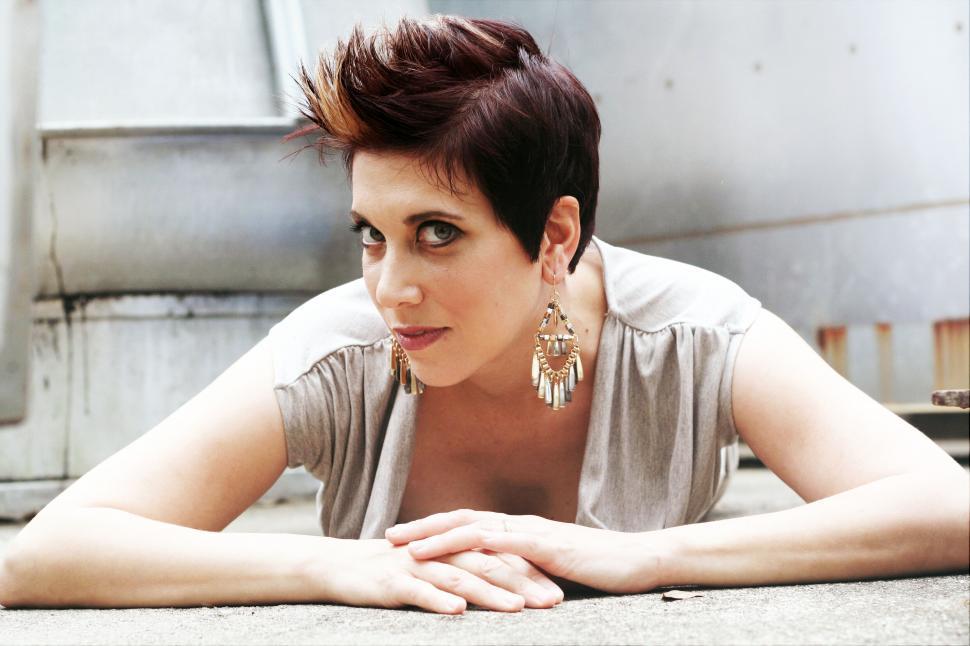 Free Image of Woman lying down on concrete with earrings 