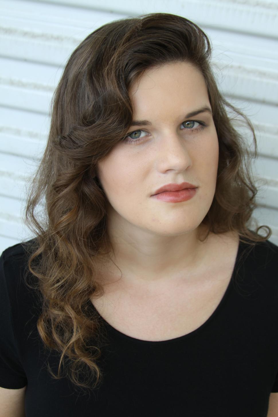 Free Image of Brunette in black top with neutral backdrop 