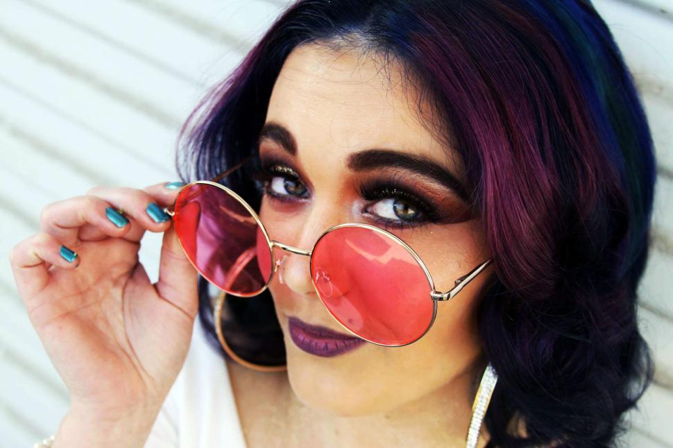 Free Image of Woman holding shaded glasses near hair 
