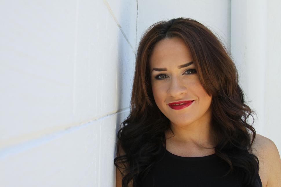 Free Image of Woman smiling against a white wall 