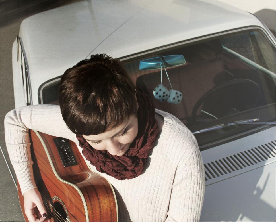 Free Image of Man playing guitar by the vintage car 