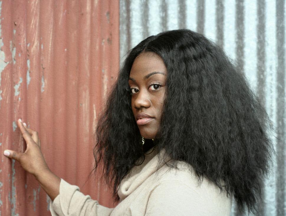 Free Image of Young woman posing by rusty corrugated iron 