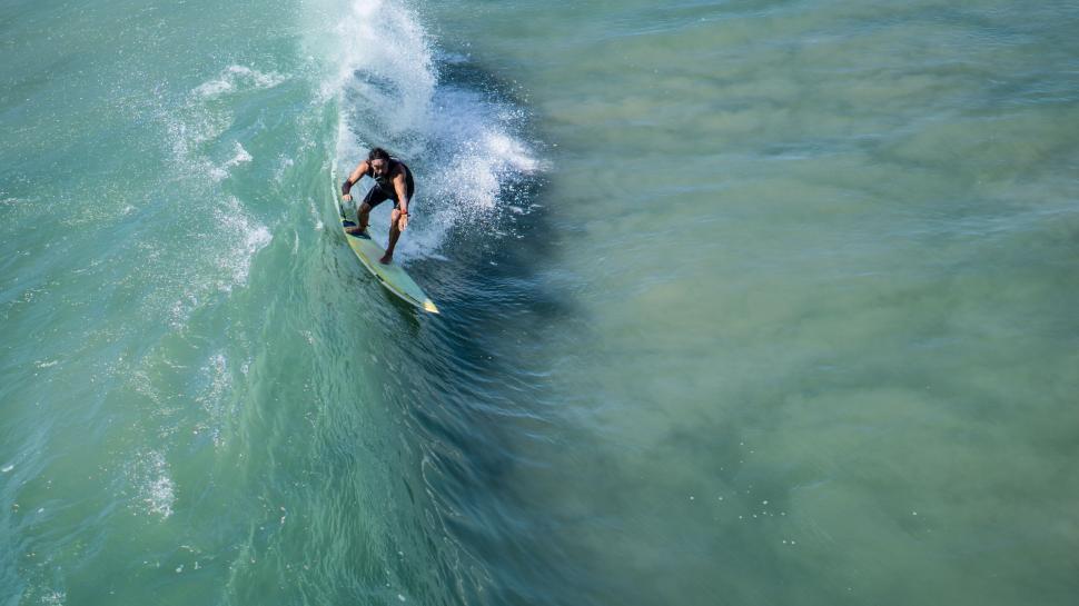 Free Image of Solo surfer riding a blue wave 