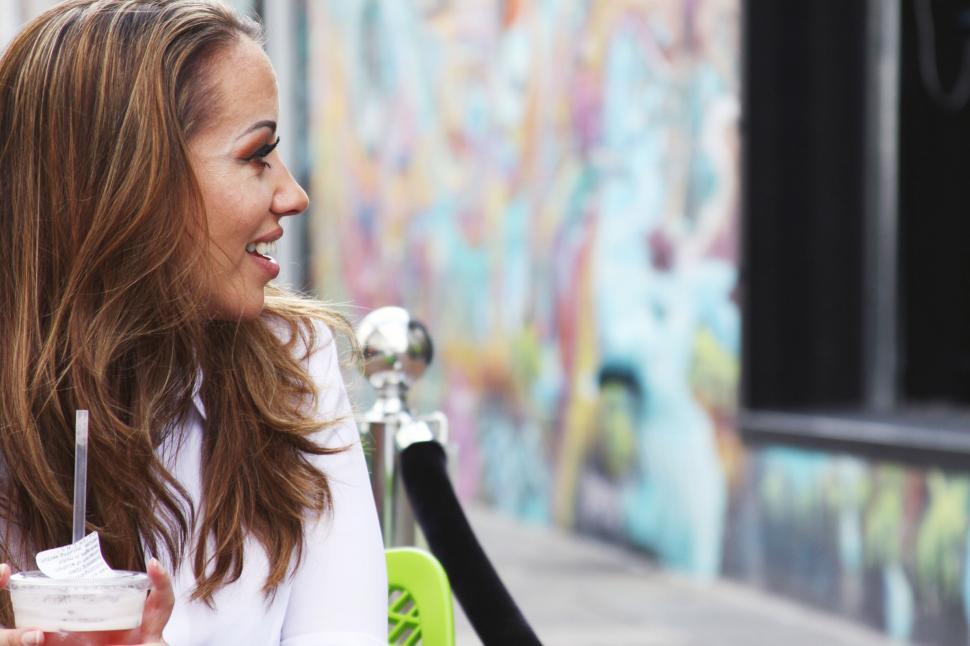 Free Image of Woman sitting with a drink in urban setting 