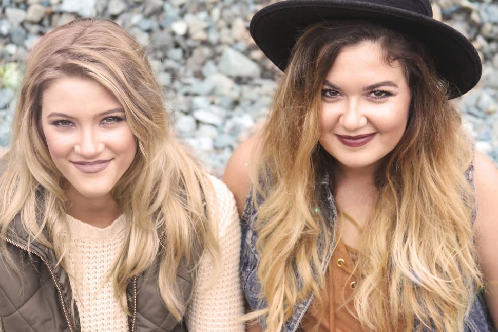 Free Image of Two smiling friends sitting together outdoors 