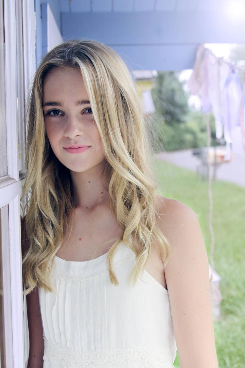 Free Image of Smiling blonde girl by a house 