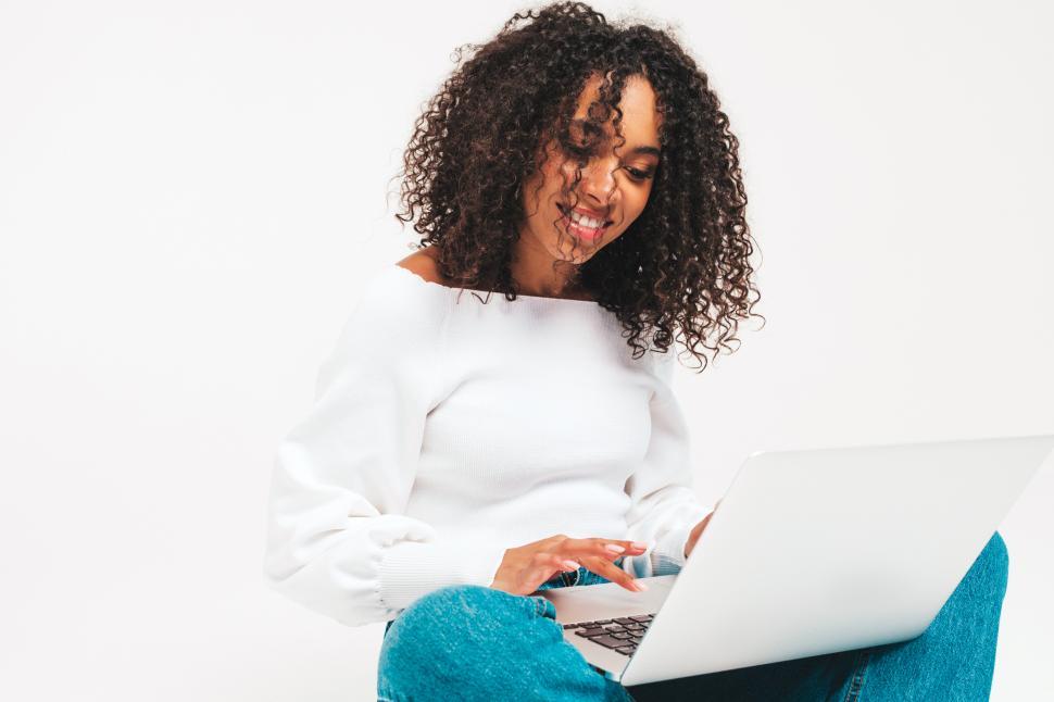 Free Image of A woman sitting on the floor using a laptop 