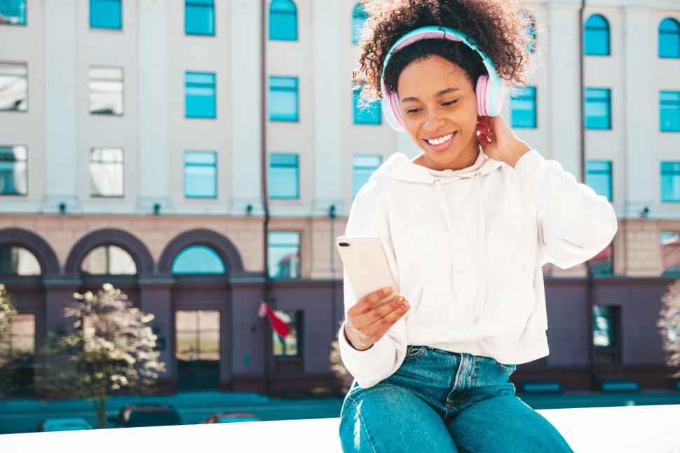 Free Image of A woman wearing headphones and looking at a phone 