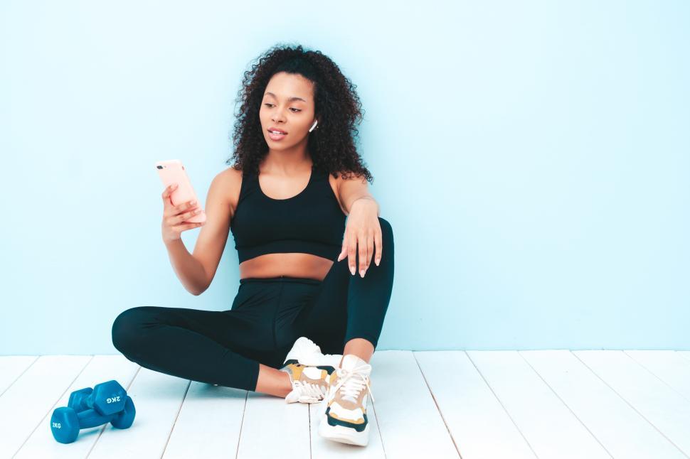Free Image of A woman sitting on the floor with a phone in her hand 