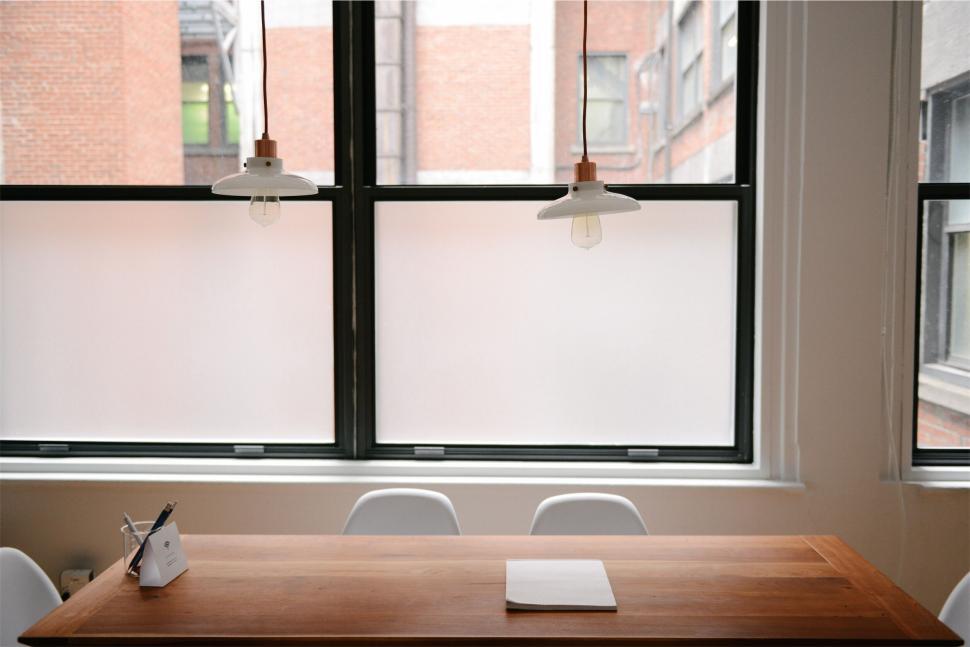 Free Image of Bright workspace with wooden table and white chairs 