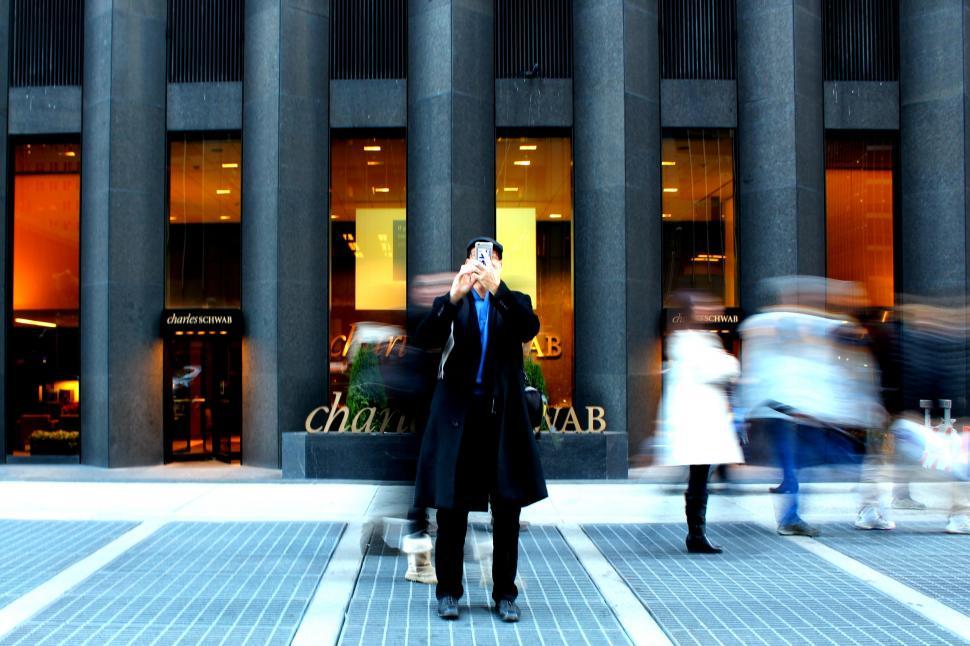 Free Image of Man photographing in front of a modern building 
