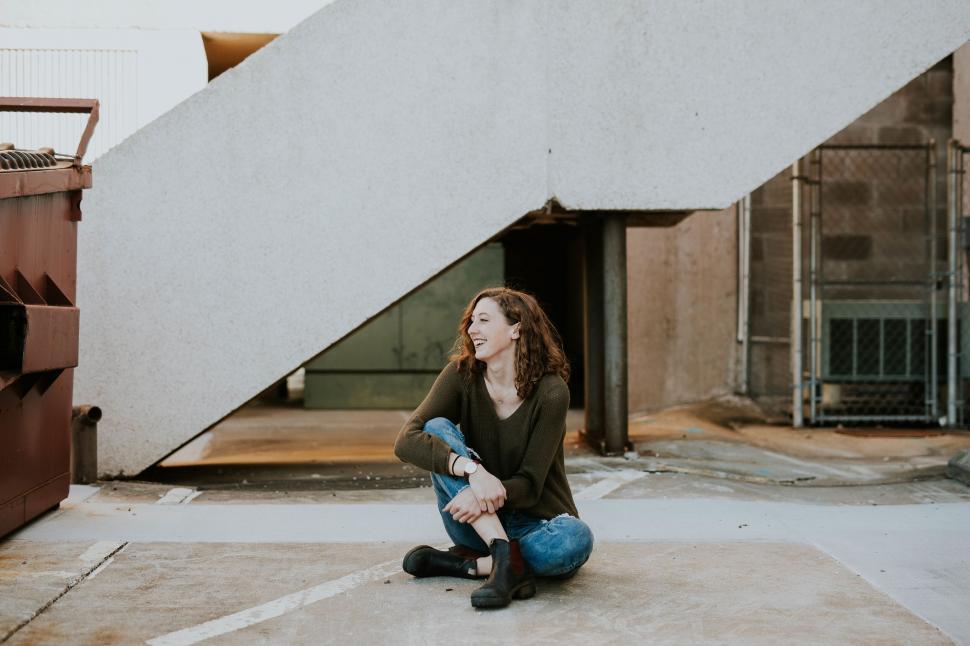 Free Image of Woman squatting on ground in industrial area 