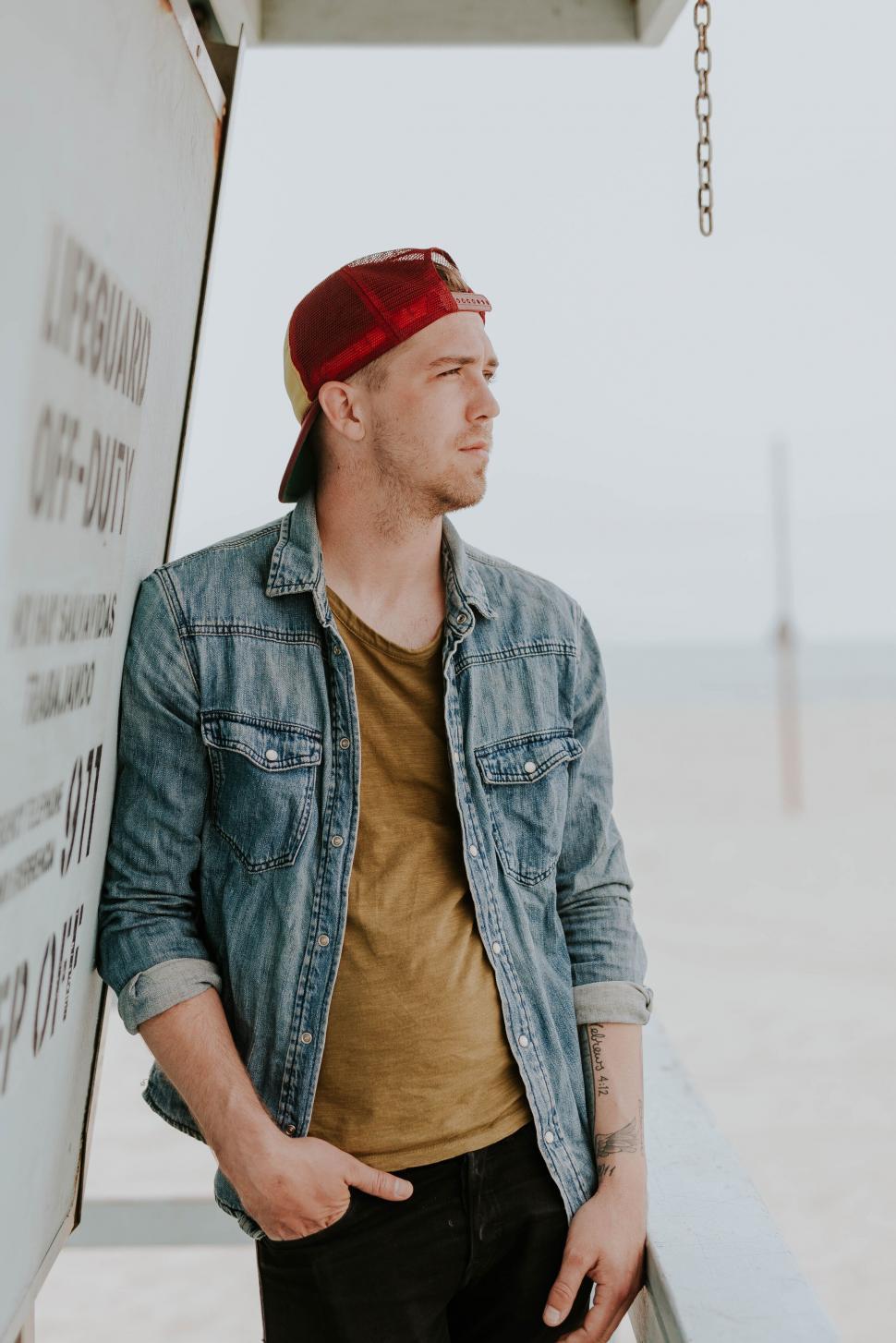 Free Image of Man leaning against a lifeguard booth 