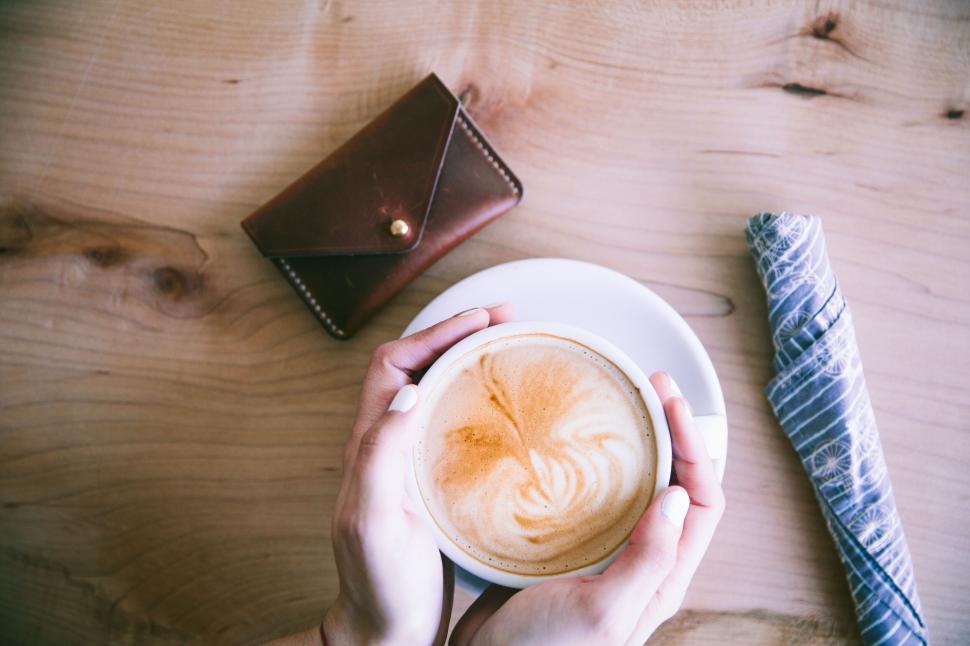 Free Image of Top view of a hand holding a latte cup 