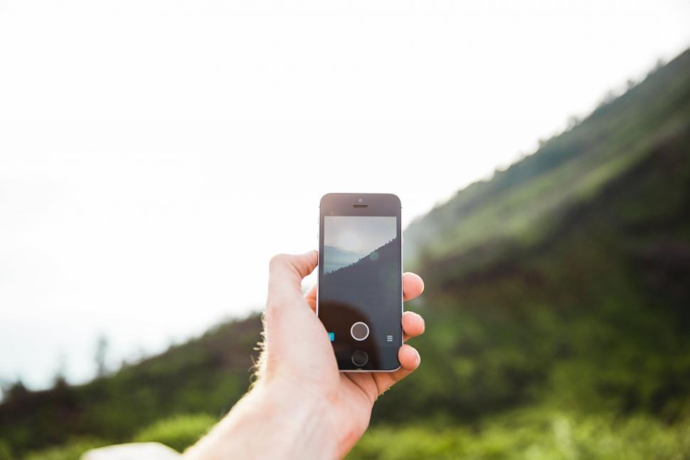 Free Image of Hand holding a smartphone capturing landscape 