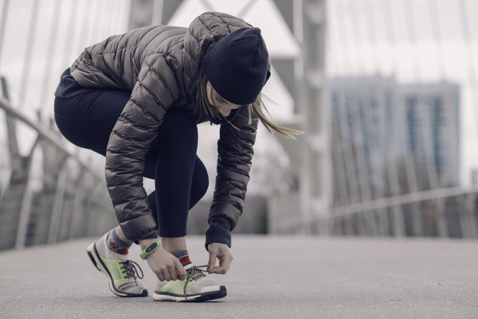 Free Image of Female runner tying shoelaces on bridge 