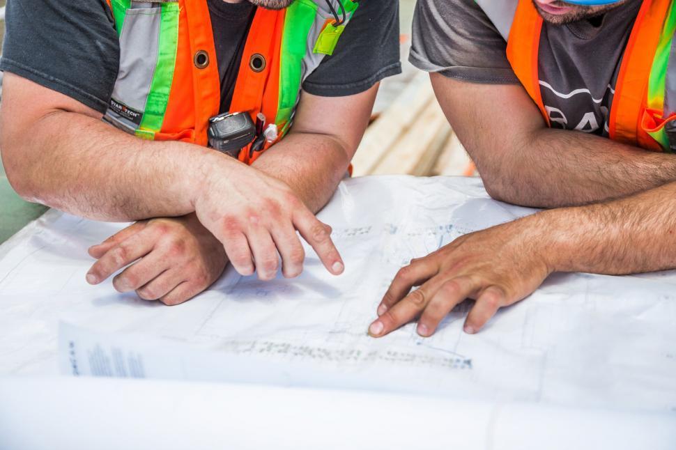 Free Image of Engineers planning over a blueprint at work 