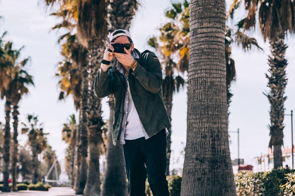 Free Image of Casual man taking photo outdoors with smartphone 
