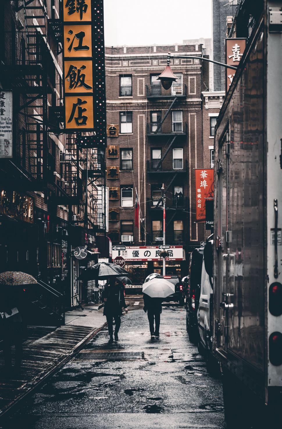 Free Image of Umbrellas and signs in a bustling city street 
